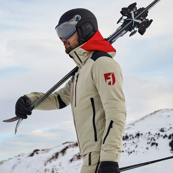 Man carrying skis wearing Toni Sailer ski wear